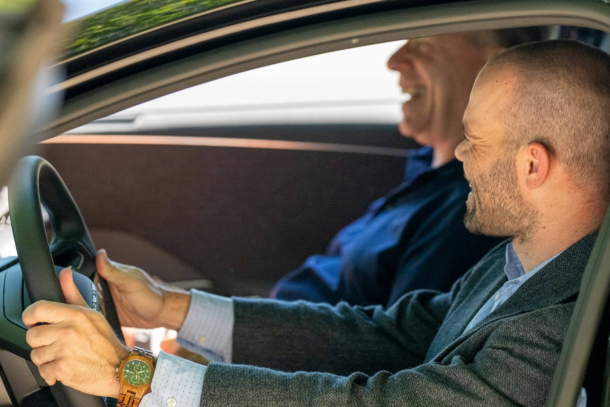 Rijinstructeur en leerling lachen samen in de auto tijdens een rijles